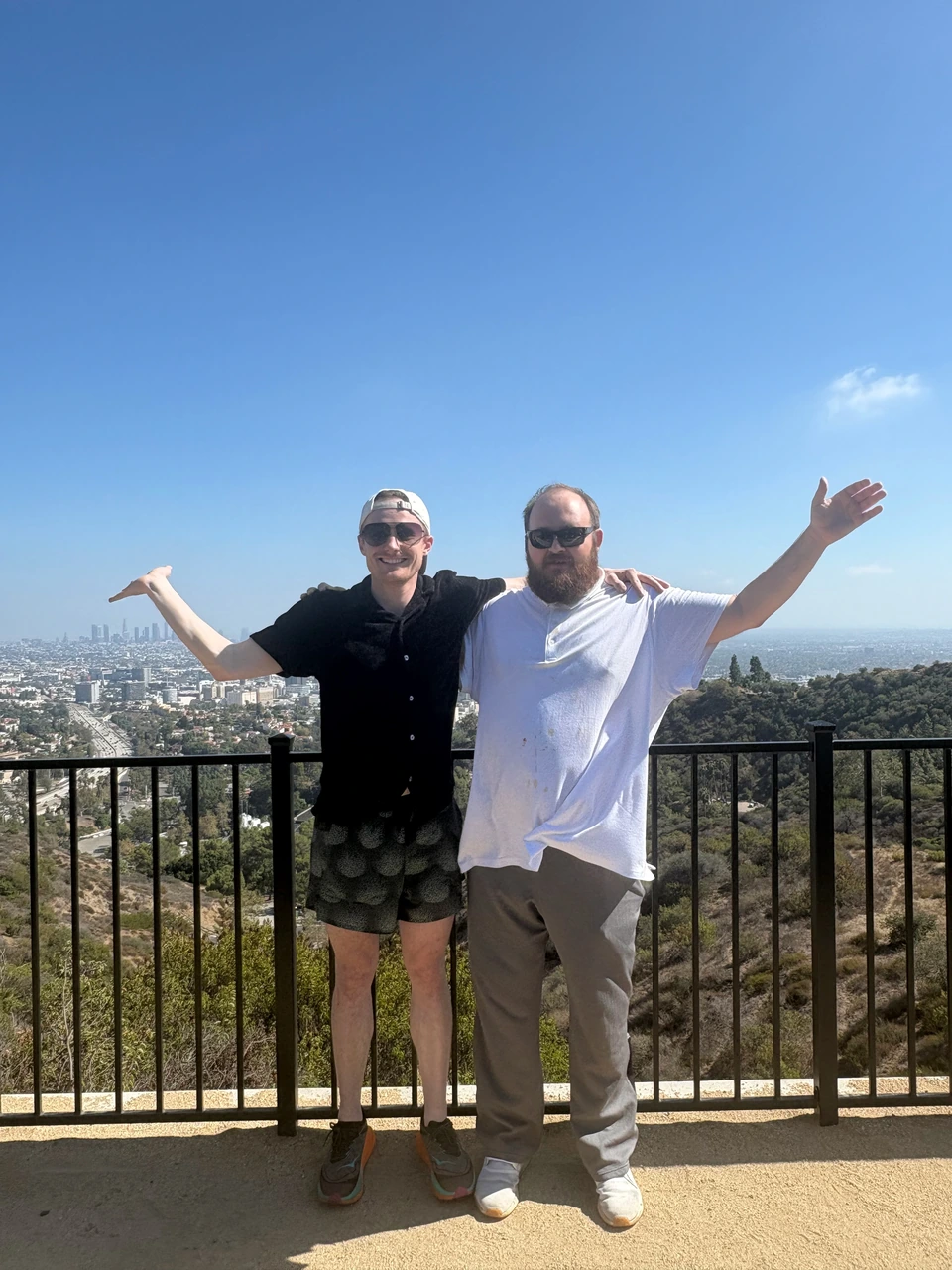 Mitchell, on the left, and his twin standing together at a scenic overlook in 2026, with their arms outstretched.